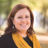 A smiling woman wearing a yellow scarf with WhatsApp Message Templates for Fashion.