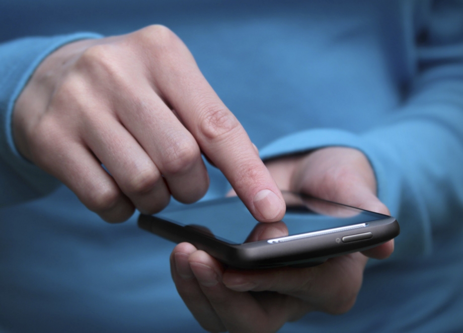 A person's hand is holding a cell phone while using messaging apps to protect users.