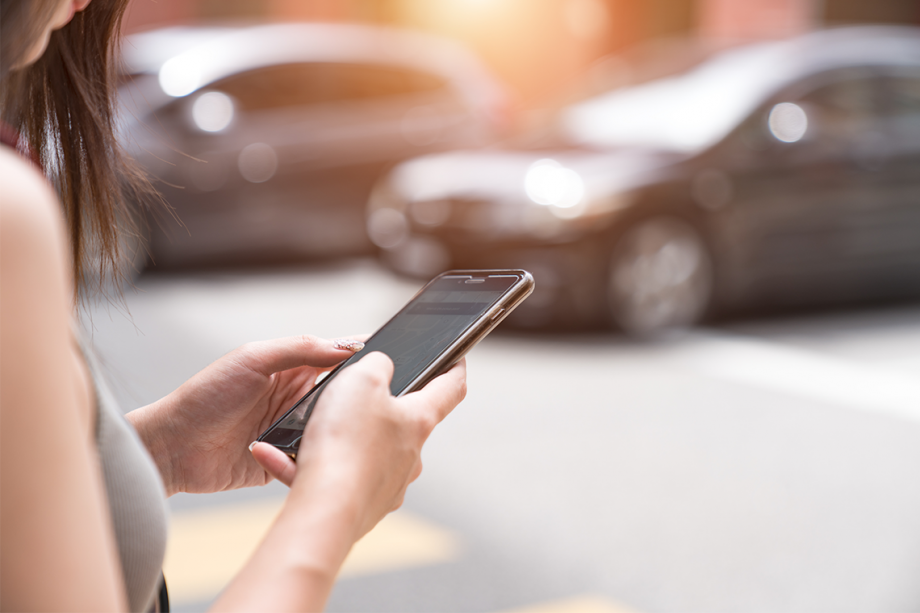 A woman is using her cell phone on the street to chat with friends on WhatsApp.