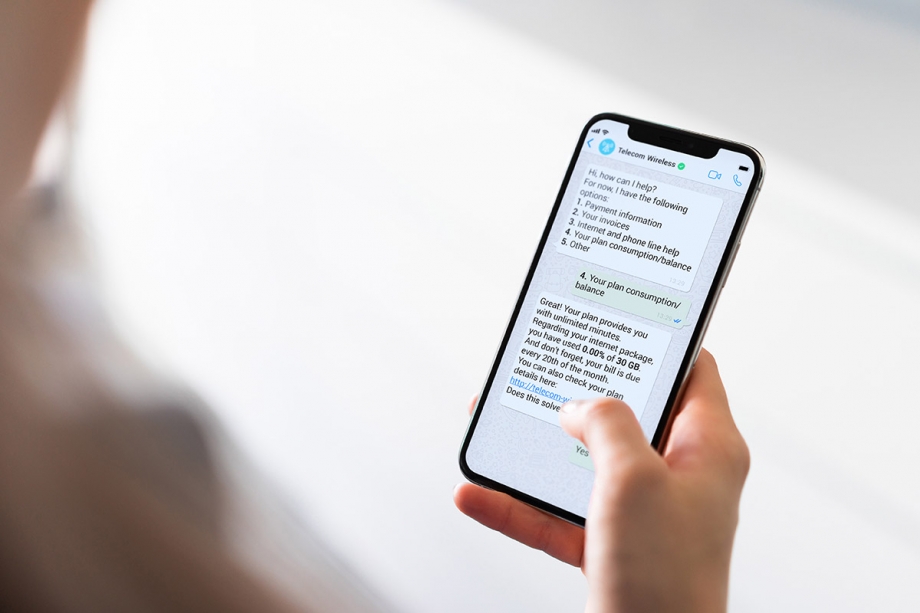 A woman holding a phone with a whatsapp message template on it.