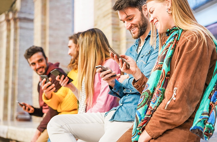 A group of people sitting on a bench engrossed in their cell phones while using WhatsApp Business.