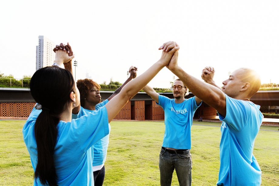 A group of people in blue t-shirts, part of a nonprofit organization, enthusiastically giving each other high fives.