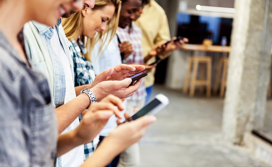 A group of people engrossed in RCS business messaging on their cell phones.