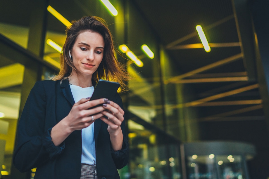 A business woman using the Microsoft Flow connector on her phone at night.