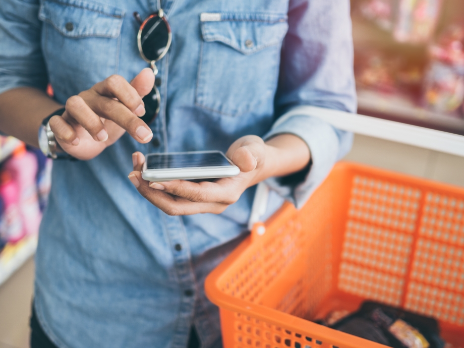 A woman holding a cell phone, incorporating Whatsapp Business in the consumer good industry.