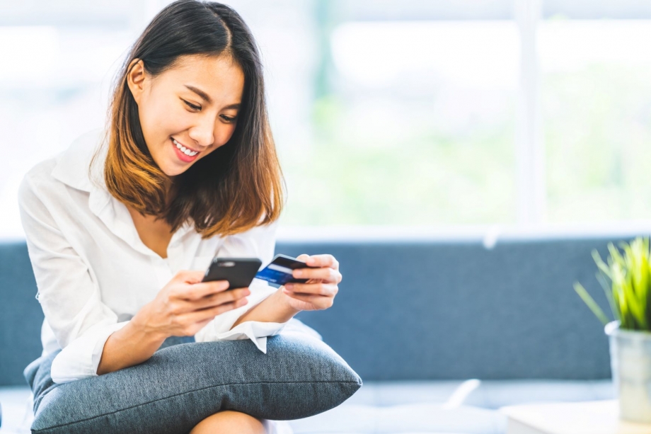 A woman is sitting on a couch and using her cell phone.