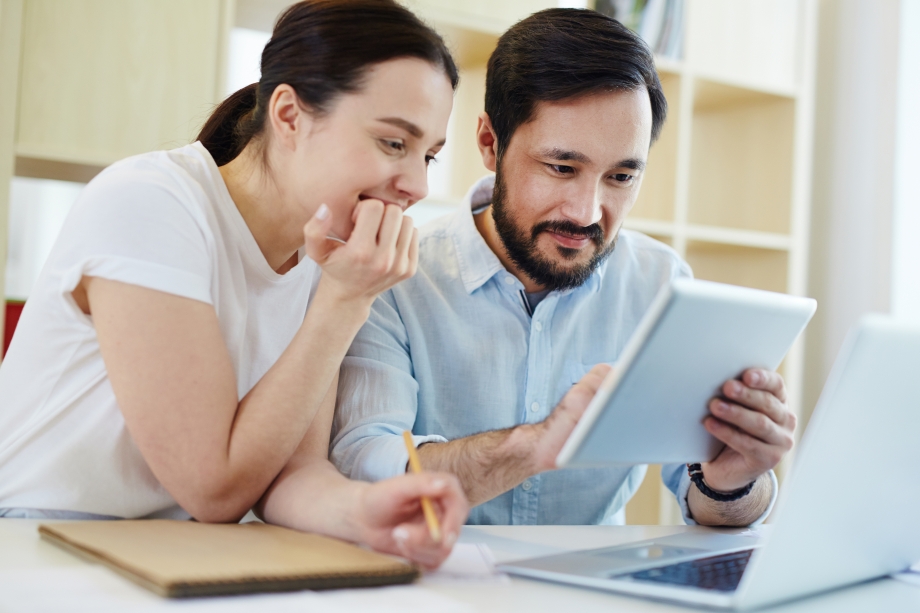 A man and woman are browsing a tablet computer, possibly on Whatsapp.