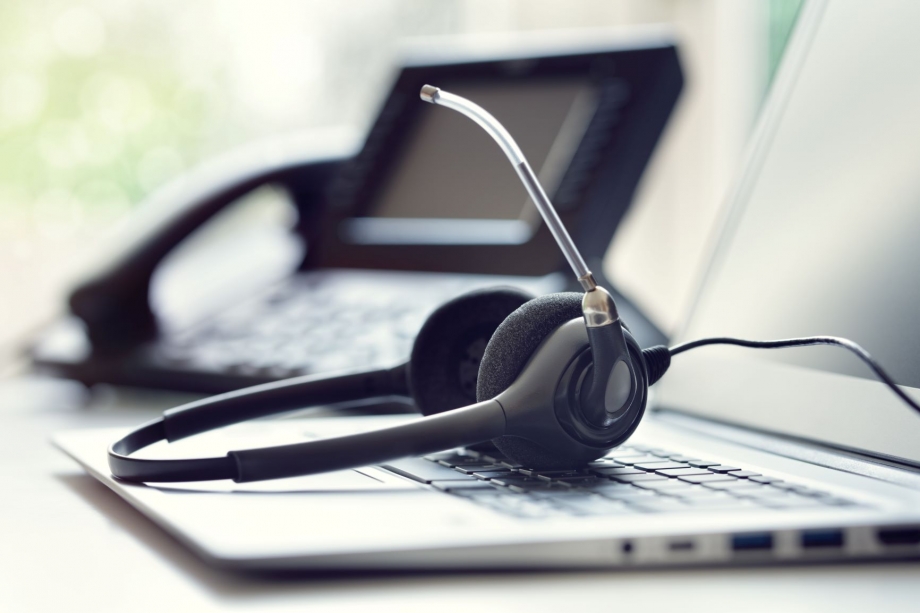 A headset sits on top of a laptop computer, allowing for seamless communication via Whatsapp.