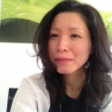 A woman is sitting in front of a green wall.